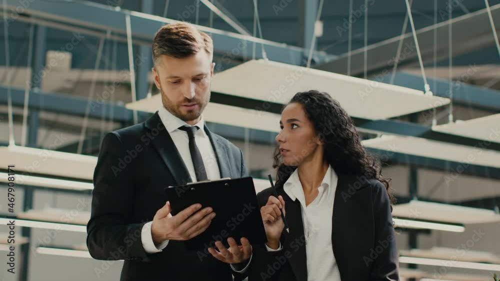 Colleagues Reading Papers Holding Clipboard Folder Discussing Work In Office