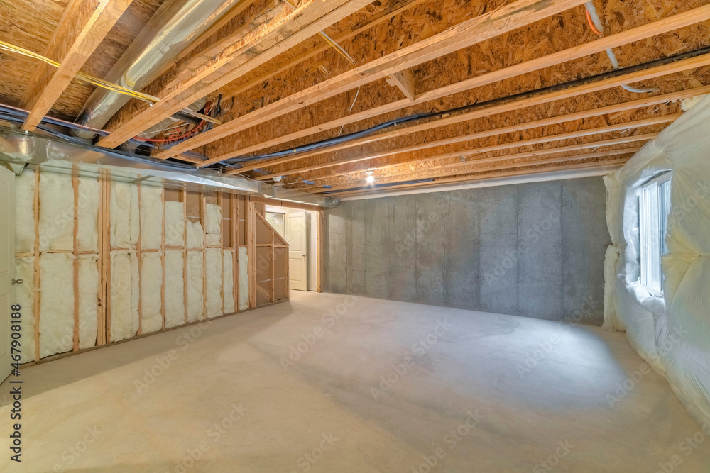 Unfinished basement with a plastic vapor barrier on the wall