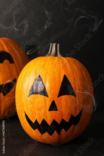 Pumpkins with drawn spooky faces on dark background. Halloween celebration