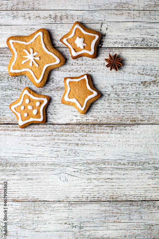 Corner of Christmas gingerbreads in the shape of a star with patterns of glaze and spices on a white wooden background. Corner of Christmas gingerbreads in the shape of a star with patterns of glaze and spices on a white wooden background.