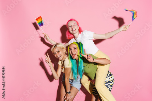 Young three women making fun with rainbow flags together