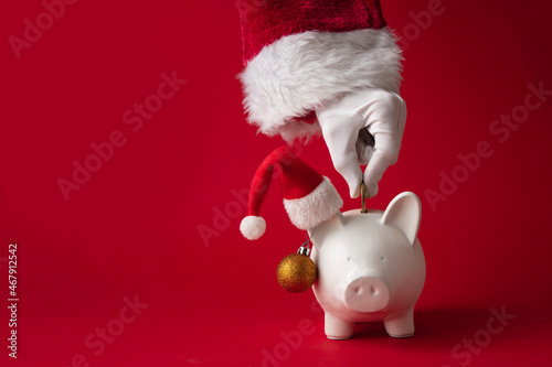 Slika na platnu Santa Claus putting money into a Christmas piggy bank money box