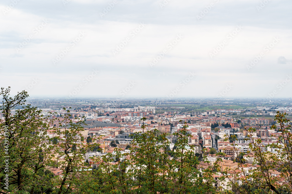 View of Bergamo through thickets of trees. Italy