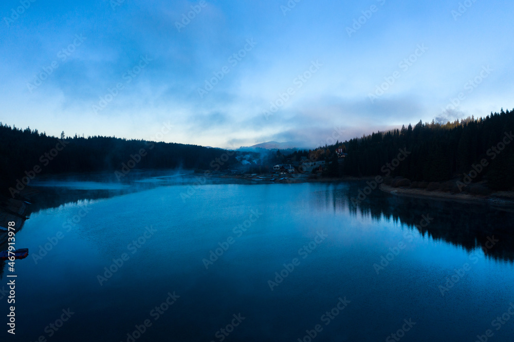 Aerial view of mountain misty lake in sunrise lights