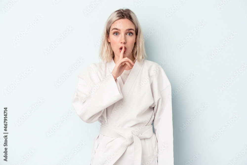 Young caucasian woman doing karate isolated on blue background keeping a secret or asking for silence. Young caucasian woman doing karate isolated on blue background keeping a secret or asking for silence.
