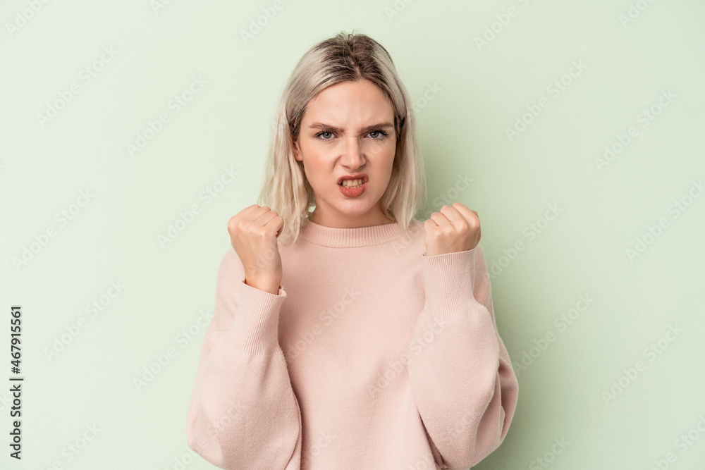 Young caucasian woman isolated on green background upset screaming with tense hands. Young caucasian woman isolated on green background upset screaming with tense hands.