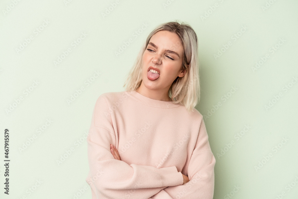 Young caucasian woman isolated on green background funny and friendly sticking out tongue. Young caucasian woman isolated on green background funny and friendly sticking out tongue.