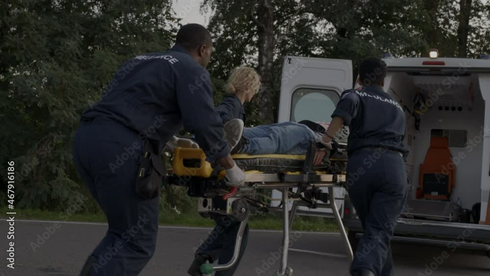 Paramedics running to ambulance car with man on stretcher