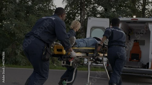 Paramedics running to ambulance car with man on stretcher