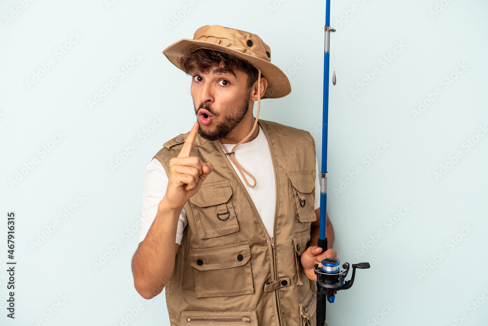 Young mixed race fisherman holding a rod isolated on blue background having an idea, inspiration concept.