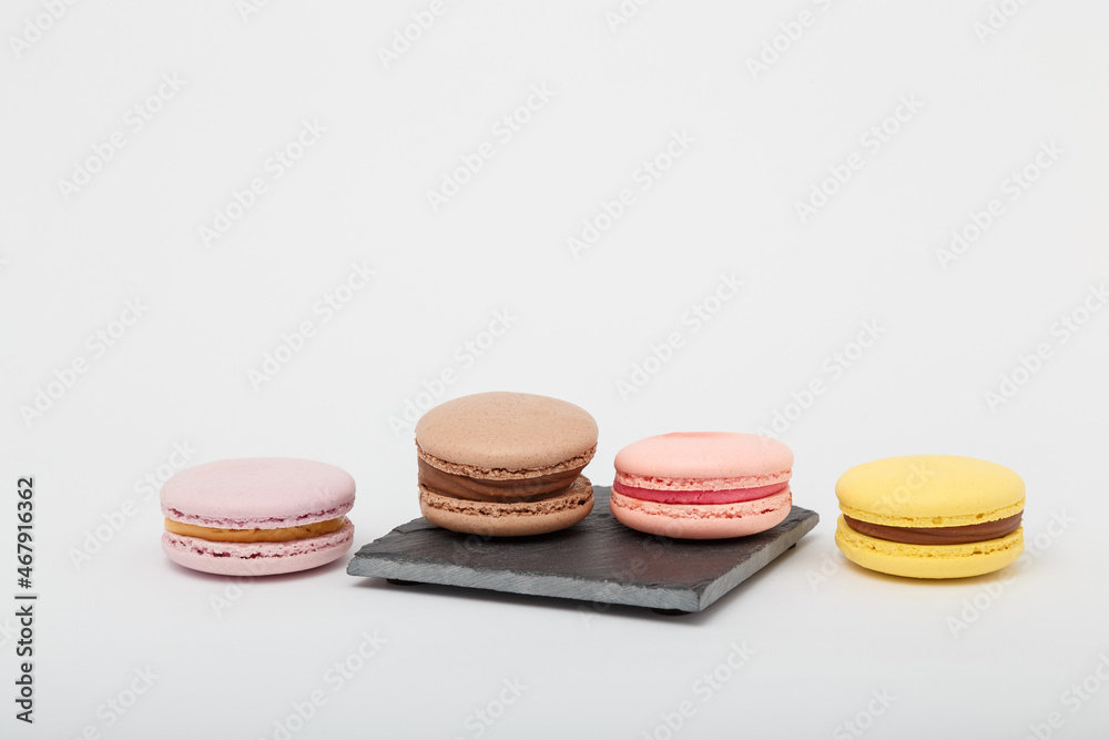 Obraz premium Colorful macaroons on grey mat on white background. Sweet bakery, copy space.