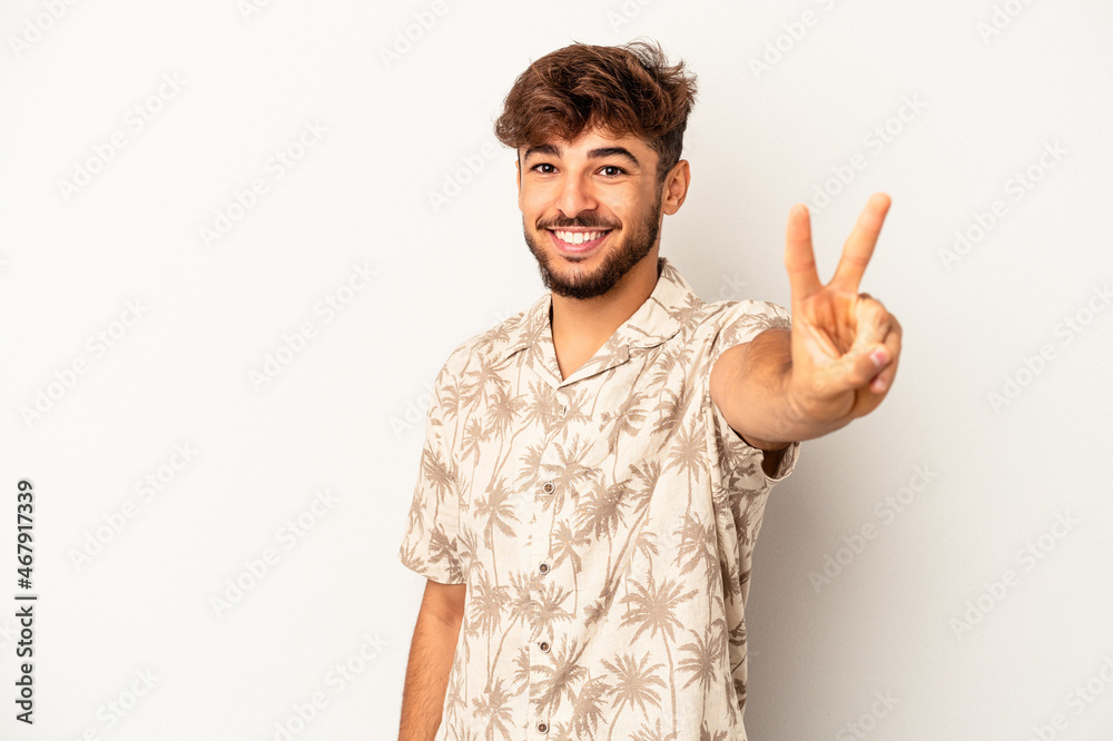 Young mixed race man isolated on grey background joyful and carefree showing a peace symbol with fingers. Young mixed race man isolated on grey background joyful and carefree showing a peace symbol with fingers.