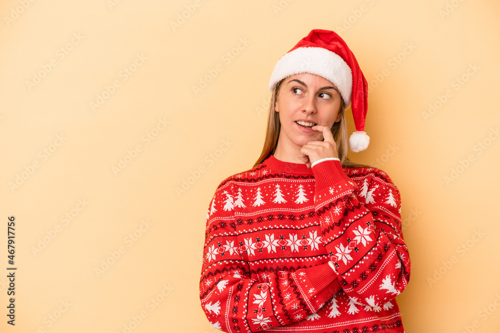 Young caucasian woman celebrating Christmas isolated on yellow background relaxed thinking about something looking at a copy space. Young caucasian woman celebrating Christmas isolated on yellow background relaxed thinking about something looking at a copy space.