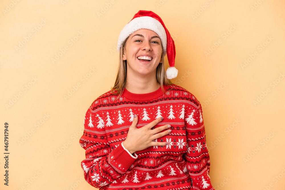 Young caucasian woman celebrating Christmas isolated on yellow background laughs out loudly keeping hand on chest. Young caucasian woman celebrating Christmas isolated on yellow background laughs out loudly keeping hand on chest.