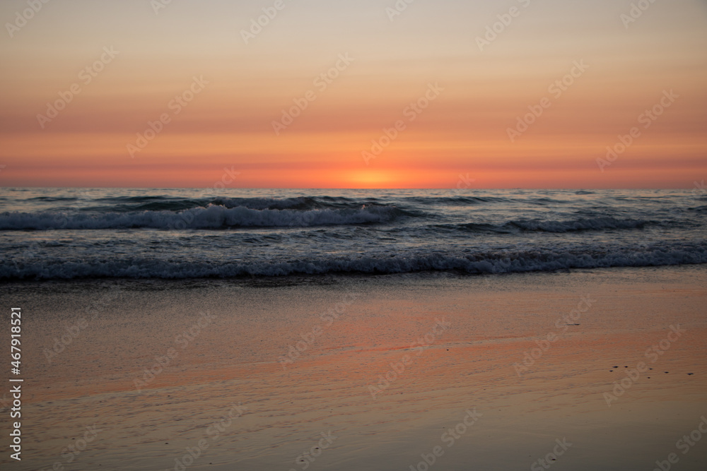 Rötlicher Sonnenuntergang am Meer mit Wellen in El Palmar Andalusien Spanien