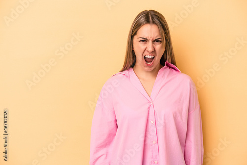 Young caucasian woman isolated on yellow background shouting very angry, rage concept, frustrated.