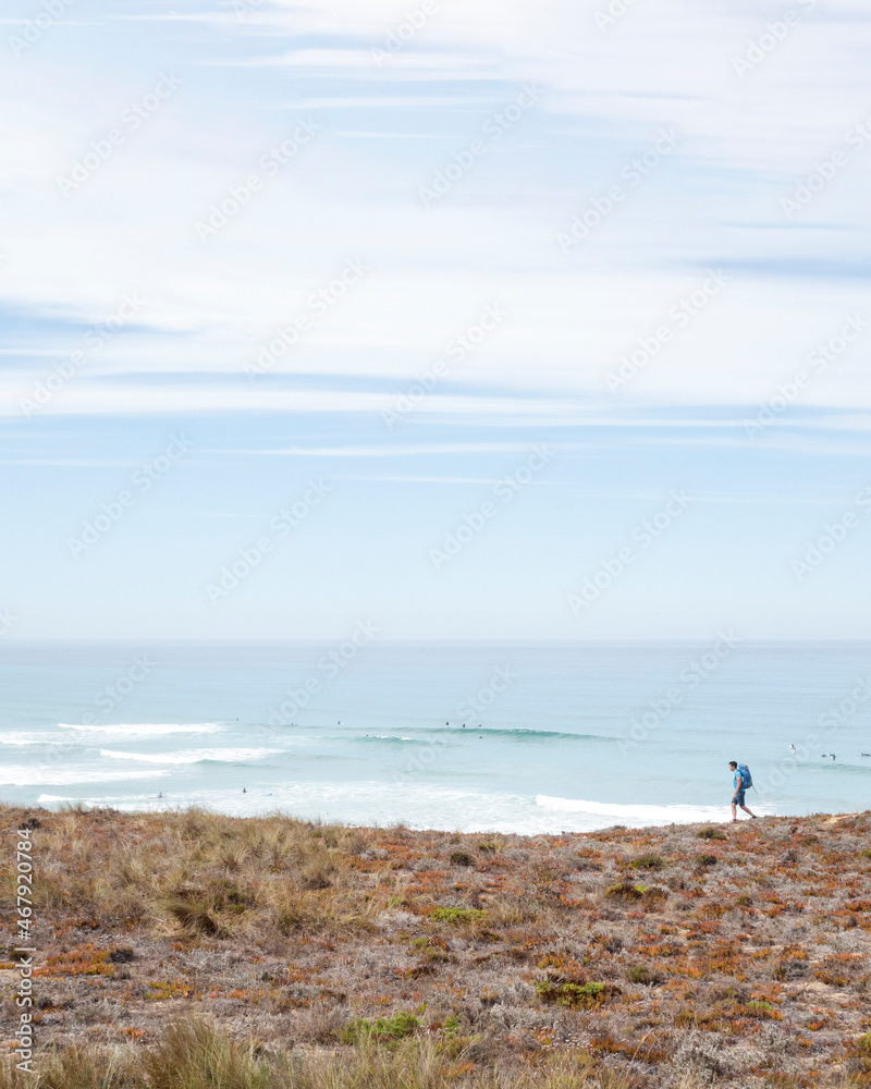 hiker walking relaxed on the beach of Brejo on the fishermen's route in Portugal on a cloudy day