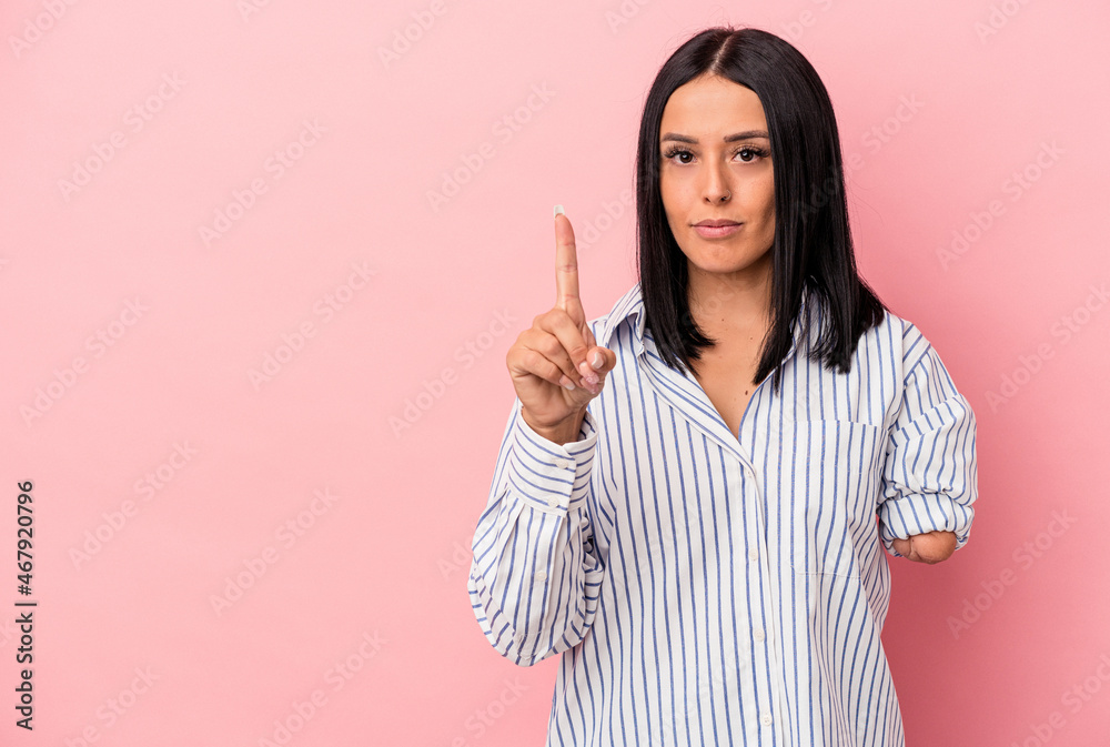 Young caucasian woman with one arm isolated on pink background showing number one with finger.
