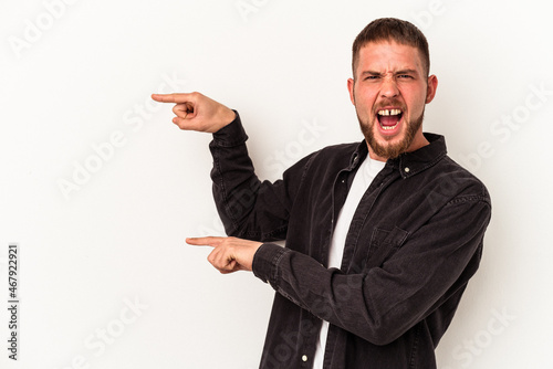 Young caucasian man with diastema isolated on white background excited pointing with forefingers away.