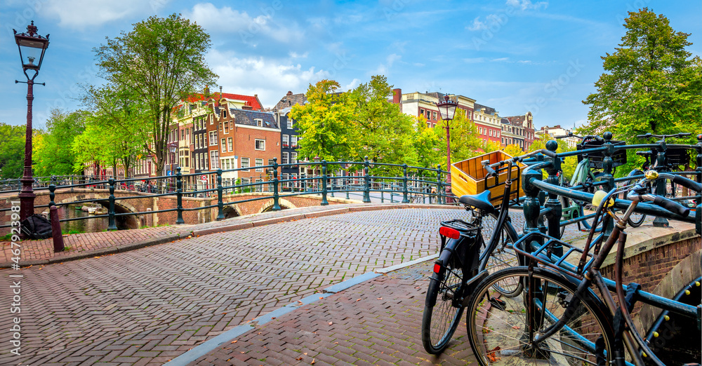 Famous Amsterdam in one photo - leaning houses, bridges, canals, bicycles and lanterns. Panorama of the famous old center of Amsterdam. Amsterdam, Holland, Europe