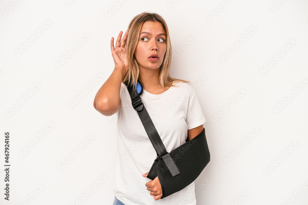 Young caucasian woman with broken hand isolated on white background trying to listening a gossip. Young caucasian woman with broken hand isolated on white background trying to listening a gossip.