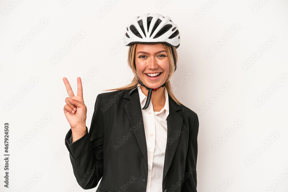 Young caucasian business woman wearing a bike helmet isolated on white background joyful and carefree showing a peace symbol with fingers. Young caucasian business woman wearing a bike helmet isolated on white background joyful and carefree showing a peace symbol with fingers.