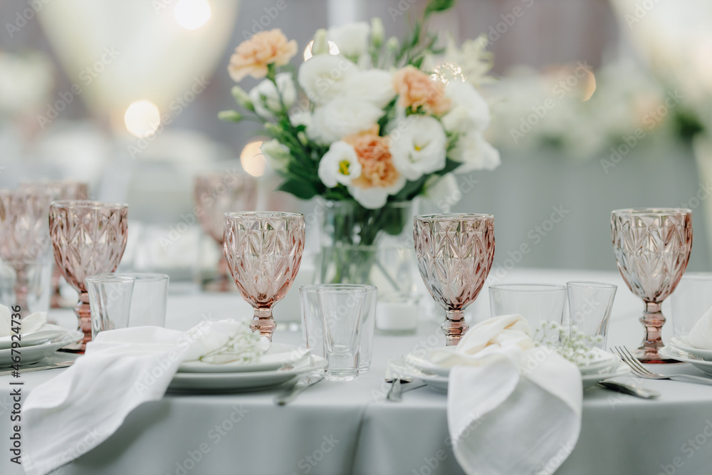 banquet table is decorated with plates, cutlery, glasses and flower arrangements