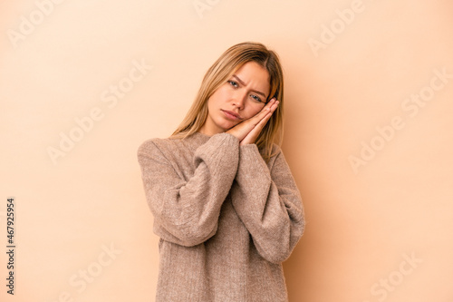 Young caucasian woman isolated on beige background yawning showing a tired gesture covering mouth with hand.