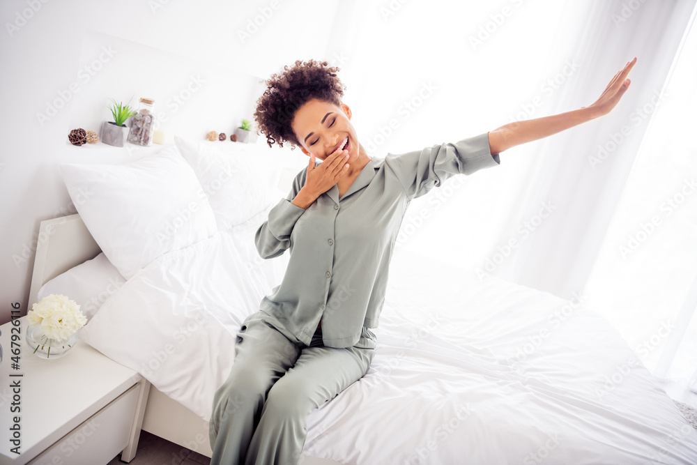 Photo of positive lady wake up stretch hands yawn cover mouth wear silky gown in light bedroom home indoors
