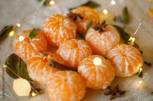 Fresh Clementines or Tangerines in the Basket on Brown Wooden Table with Xmas Lights and Tree Branches