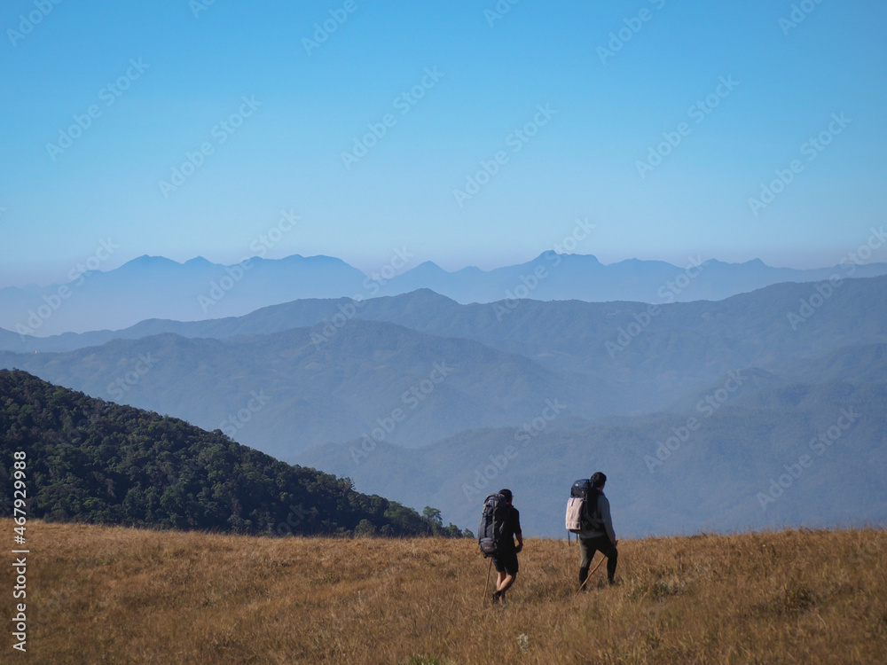Obraz premium Two backpacker are trekking along the way at Monjong Chiangmai with beautiful view of mountain range