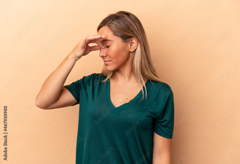 Young caucasian woman isolated on beige background having a head ache, touching front of the face. Young caucasian woman isolated on beige background having a head ache, touching front of the face.