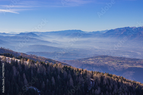 Winter landscape of the Italian mountains. View of the Belluno Dolomites from Nevegal. Mountains with light haze illuminated by the sun. Climate change concept. photo