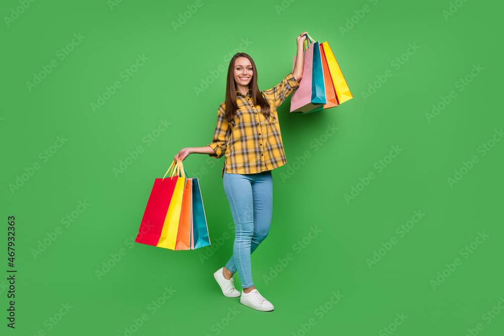 Full length photo of pretty cheerful person hold packages toothy smile isolated on green color background