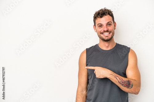 Young caucasian man isolated on white background smiling and pointing aside, showing something at blank space.