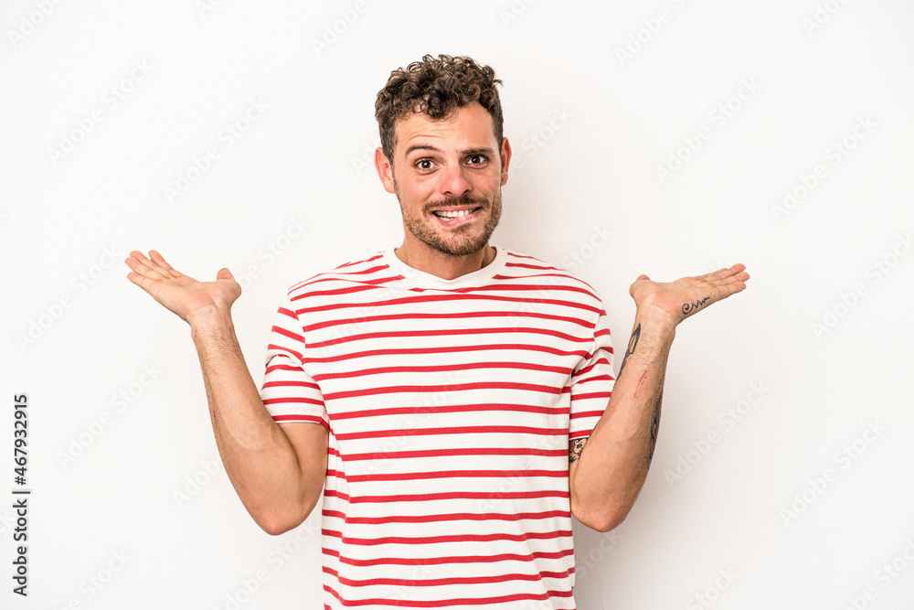 Young caucasian man isolated on white background confused and doubtful shrugging shoulders to hold a copy space. Young caucasian man isolated on white background confused and doubtful shrugging shoulders to hold a copy space.