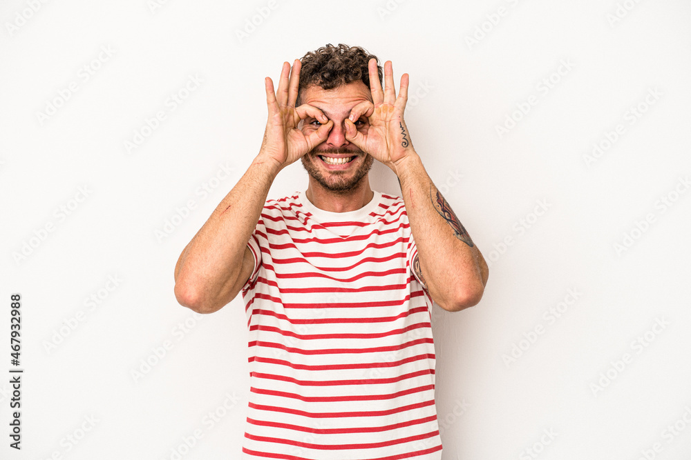 Young caucasian man isolated on white background showing okay sign over eyes Young caucasian man isolated on white background showing okay sign over eyes