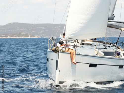 A woman reads a book on the bow of a sailing yacht. Luxurious life on a white yacht. Psychological relaxation and outdoor recreation. Yachting availability for people of average income. Beautiful