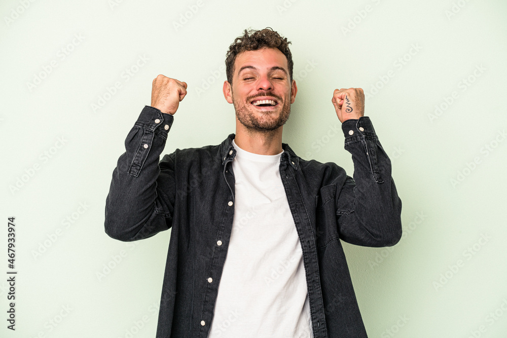 Naklejka premium Young caucasian man isolated on green background celebrating a victory, passion and enthusiasm, happy expression.