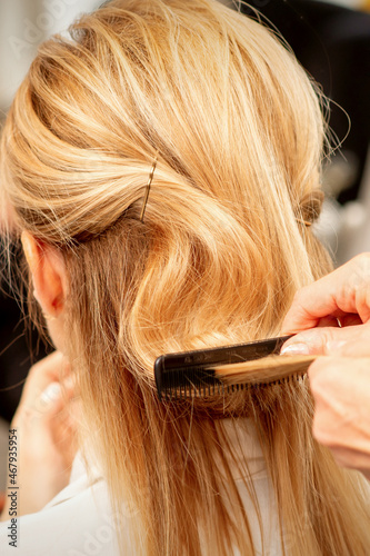 A hairdresser is combing female hairstyling in a hairdressing beauty salon