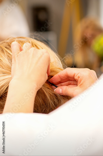 Hair stylist's hands doing professional hairstyling of female long hair in a beauty salon