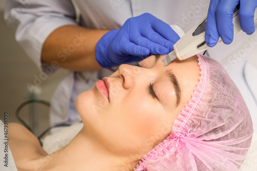 Young caucasian woman having ultrasonic peeling with ultrasound device in a cosmetic beauty salon