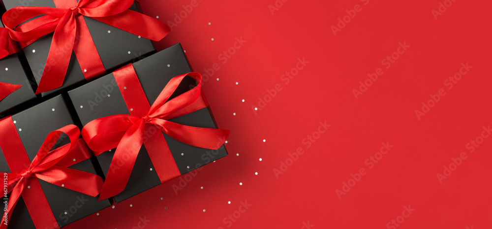 Top view photo of black gift boxes with red ribbon bow and confetti on ...