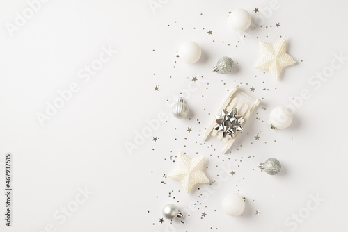 Top view photo of white and silver christmas tree decorations small sleigh with silver star balls stars and sequins on isolated white background with copyspace