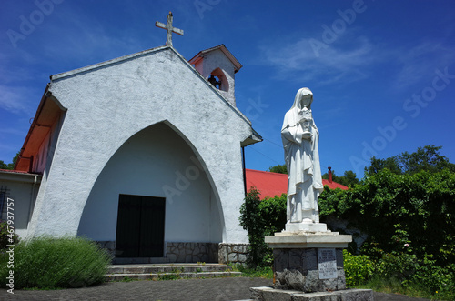 Pucon, Chile - December 6, 2018: White statue next to Santa Clara de Pucon Monastery white church, Blue sky, sunny day