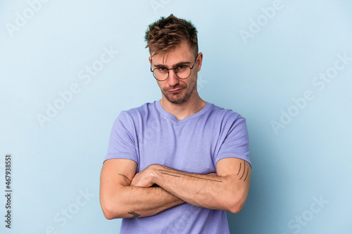 Young caucasian man isolated on blue background unhappy looking in camera with sarcastic expression.
