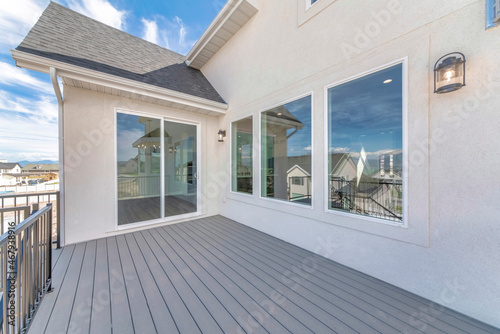 Deck of a house with reflective sliding glass door and picture windows