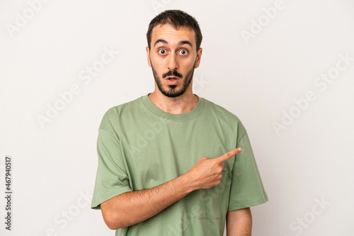 Young caucasian man isolated on white background pointing to the side