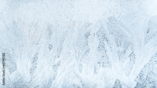 Ice pattern background. Cold winter. Christmas wonder. Extreme north. Abstract decorative frost snowflake crystals tracery on frozen white blue window pane glass surface.
