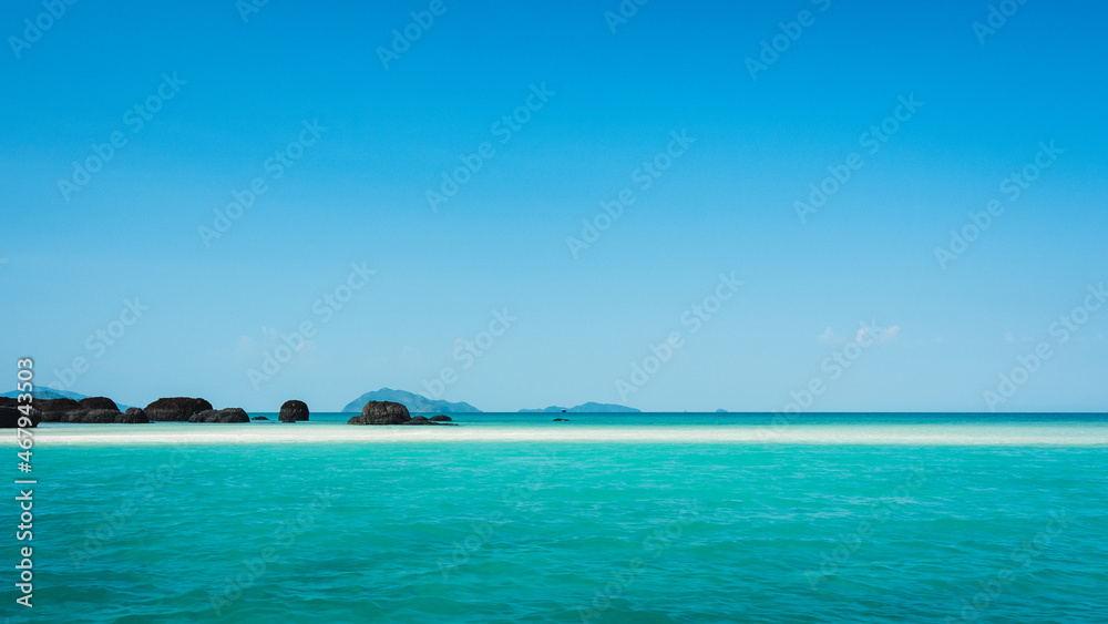 Fototapeta premium Peaceful white sand bar with iconic black volcanic rock of Koh Kham Island and crystal clear turquoise water. Near Koh Mak Island, Trat Province, Thailand.